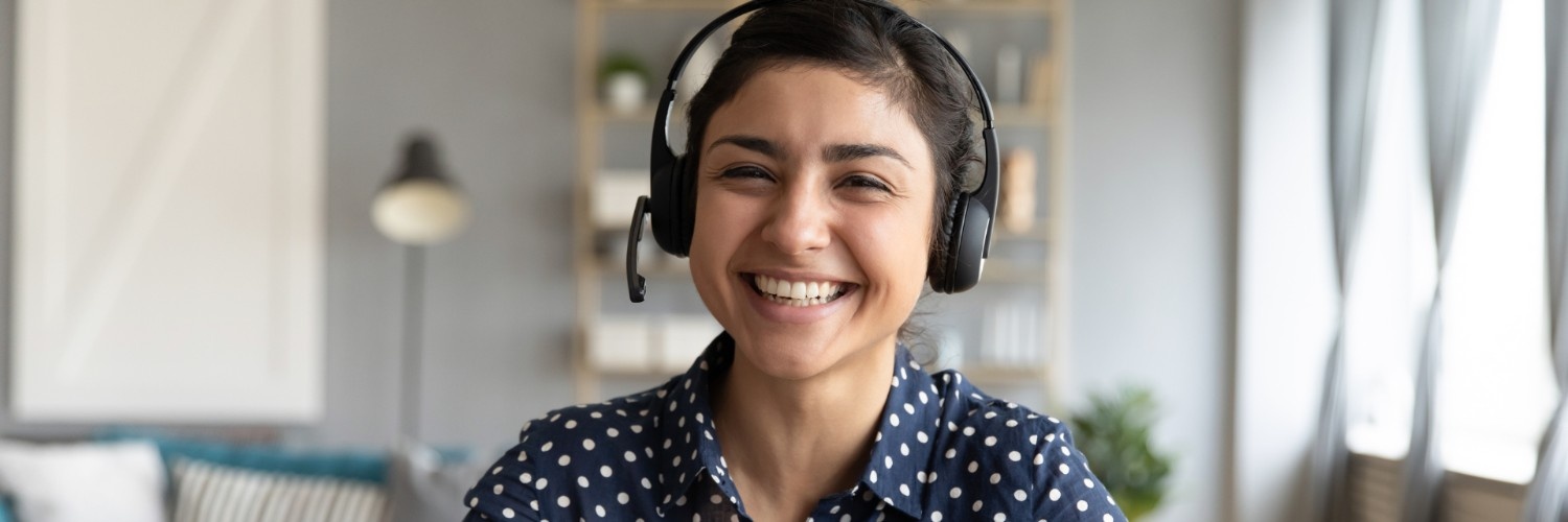 A smiling woman wearing a headset at her desk
