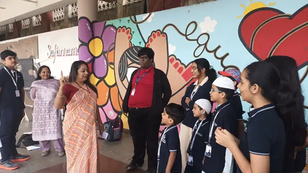 Learners and facilitators gather in front of the painted mural at Rangoli Metro Art Centre