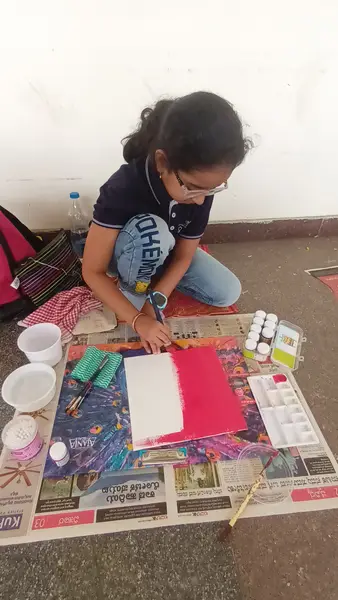 A learner painting at her spot on the floor