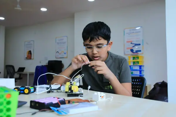 A learner in glasses wiring up a circuit board at a Learning Garage