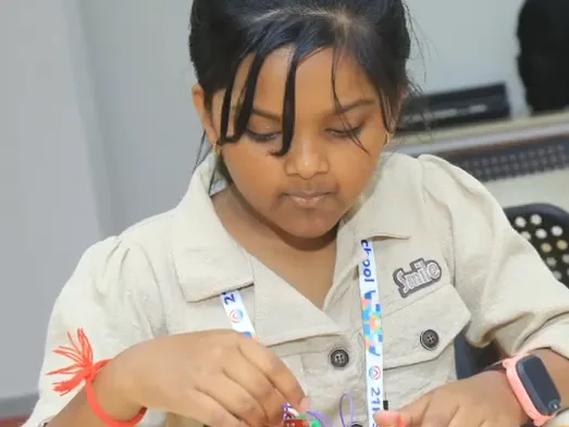 A young learner threads a wire through a kit part