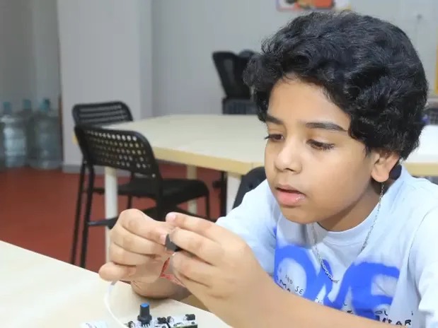 A learner fits a small sensor onto a wire at a Learning Garage table
