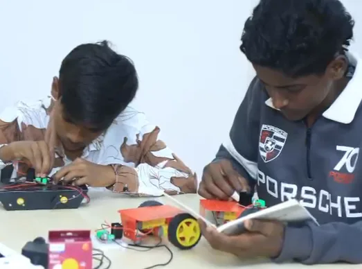 Two learners wire the motors of their robot cars