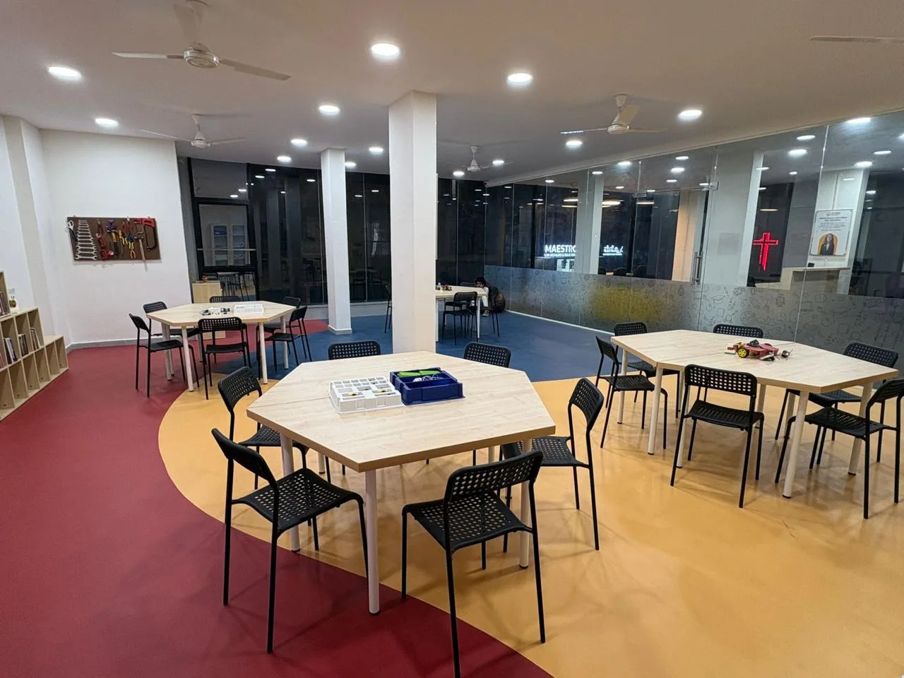 Tables set with kits across the workshop floor, the tool board and glass wall behind