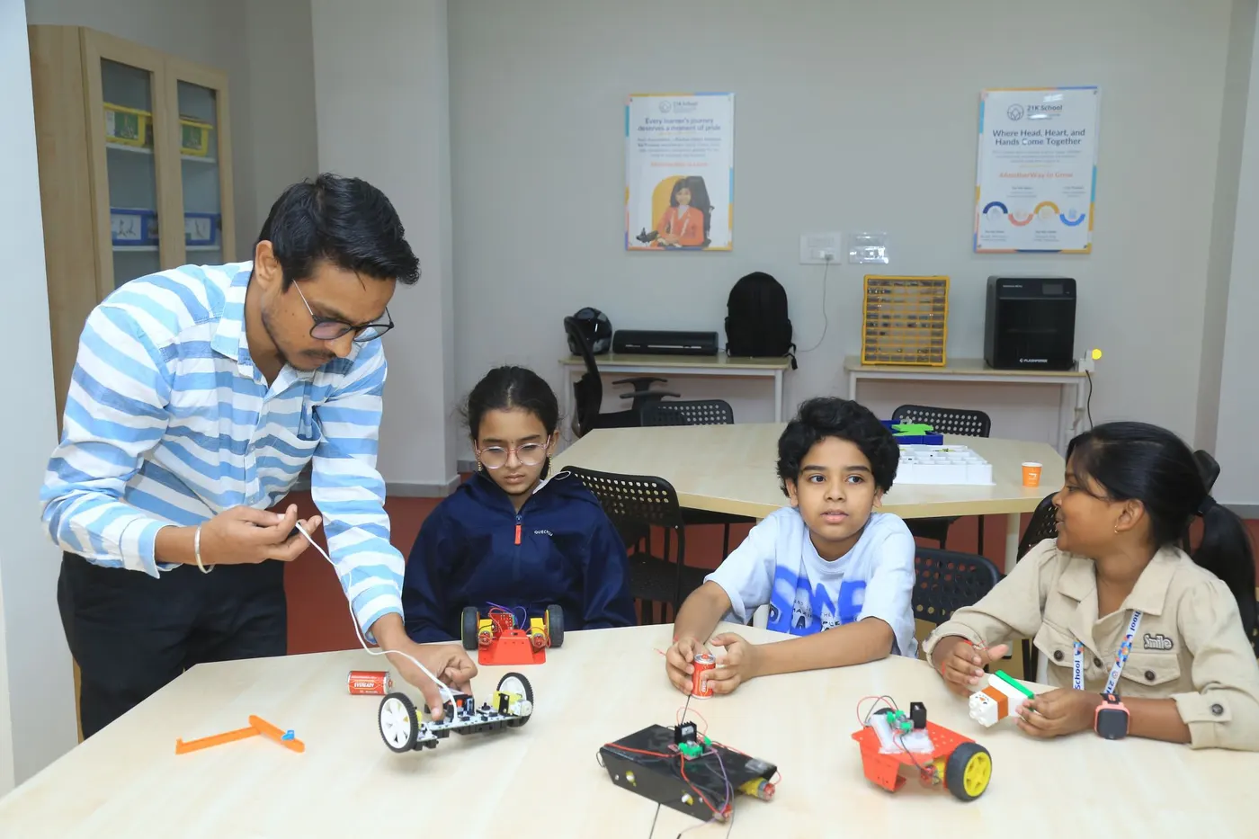 Learners build robot cars with a facilitator at a Learning Garage table