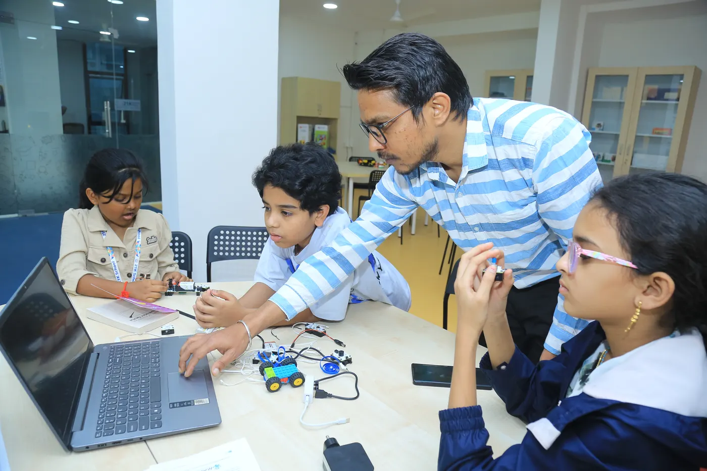 A mentor guides three learners building a robot at a Learning Garage table