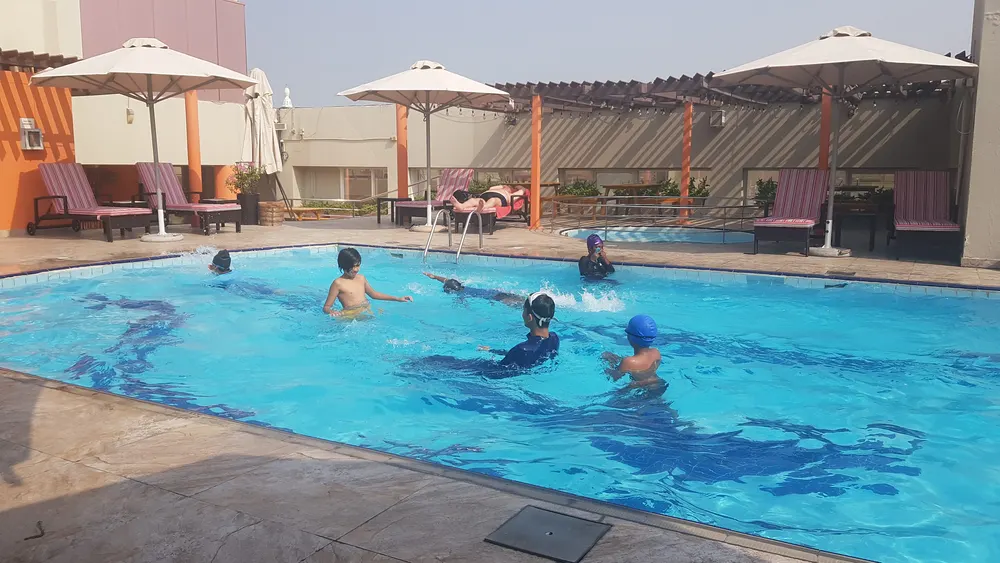 Learners swimming in a hotel pool under the Dubai sun