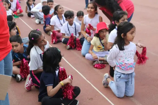 Learners with red pom-poms sitting on the track, cheering their classmates on
