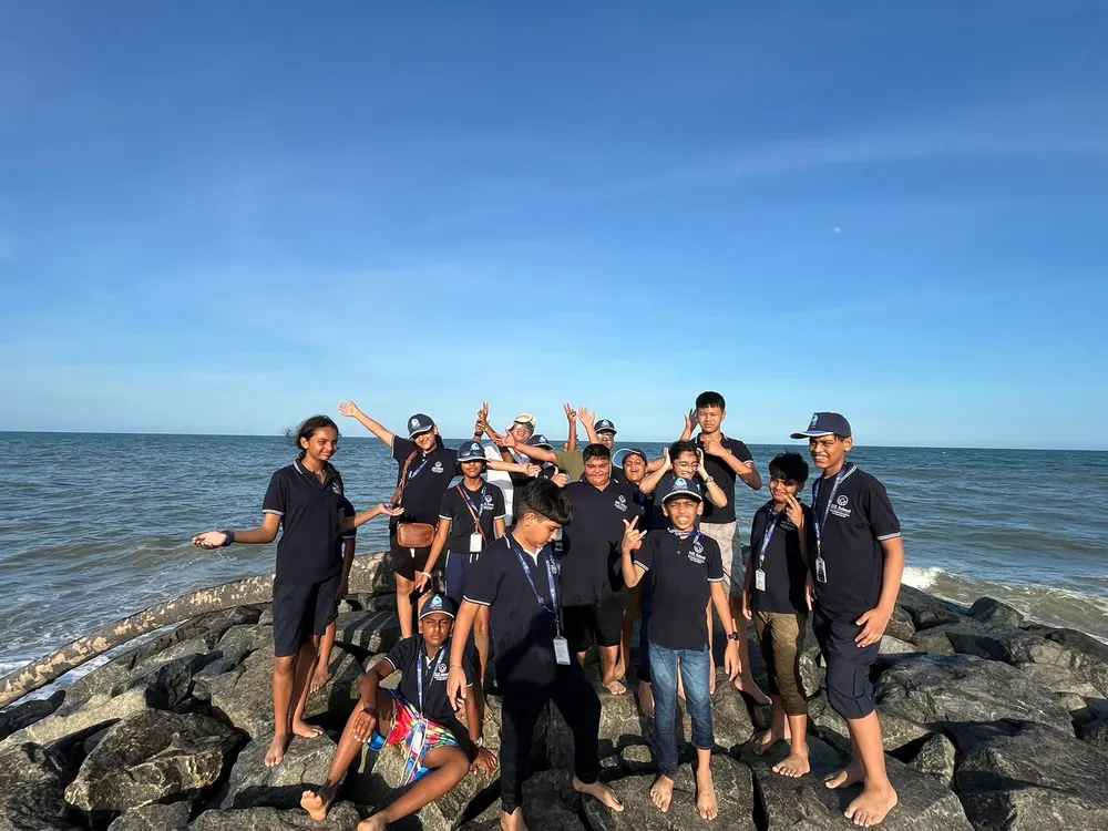 Learners posing together on the rocks by the sea