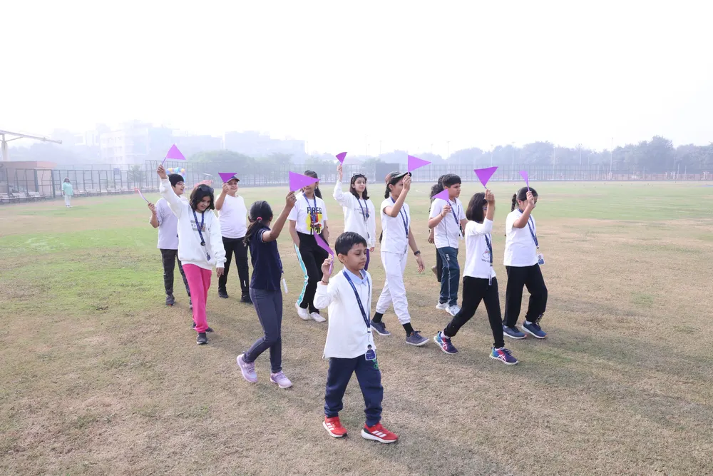Learners marching across a playing field waving flags at a Sports Day