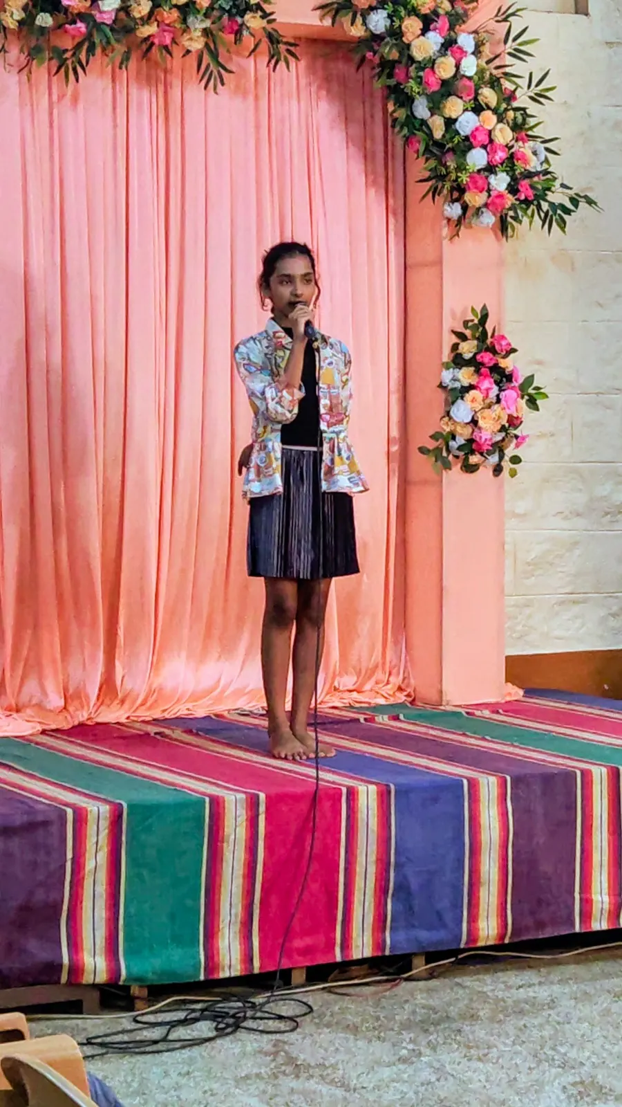 A learner speaking into a microphone on a small stage