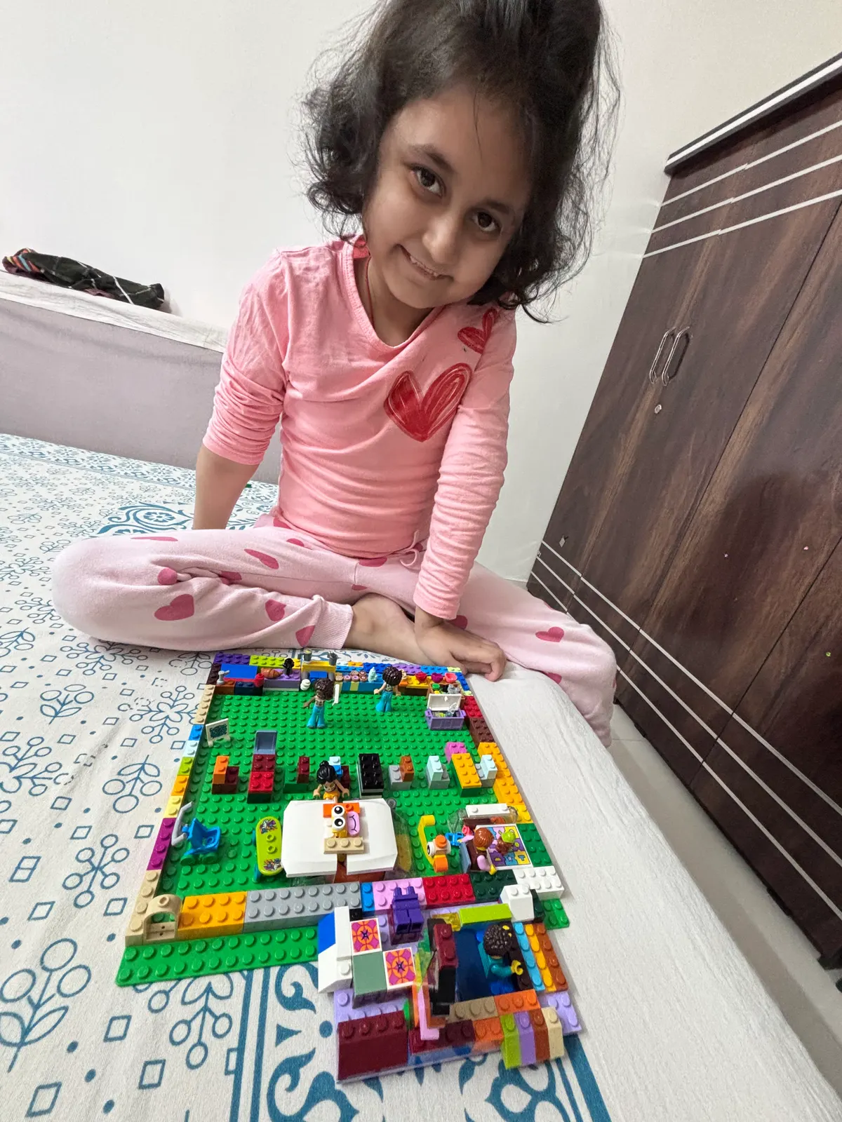 A young learner sitting beside a large town she built from construction bricks