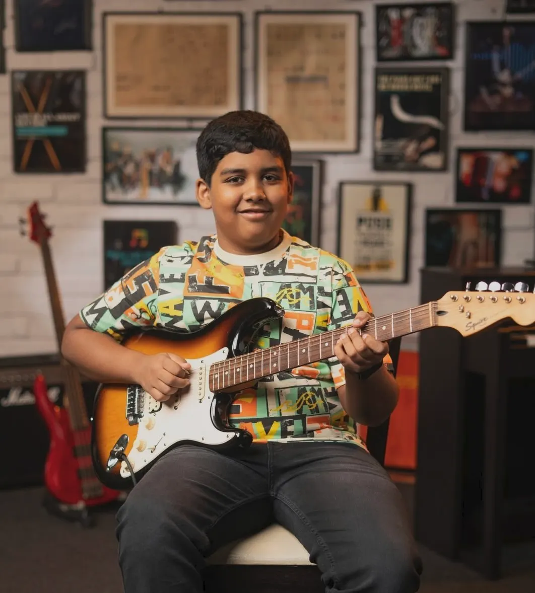 A learner playing an electric guitar in a music room