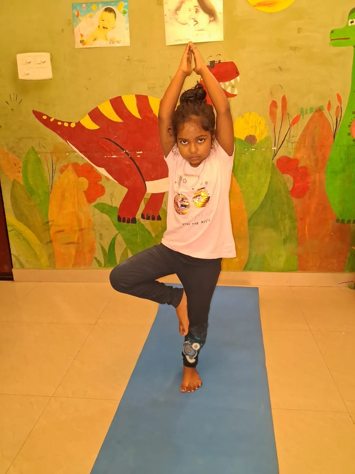 A young learner holding a yoga tree pose on a mat