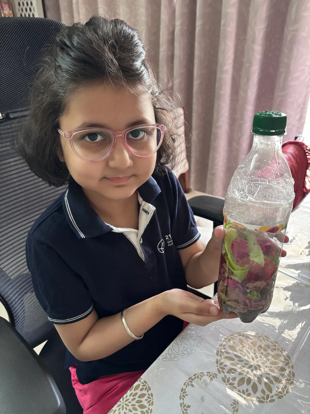 A learner in a 21K School polo holding up a bottle from a science activity