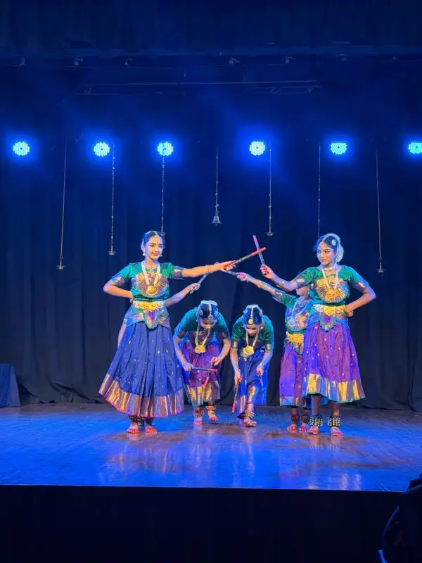 Learners performing a classical dance on a lit stage