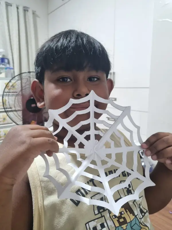 A learner showing the paper-cut spider web he made
