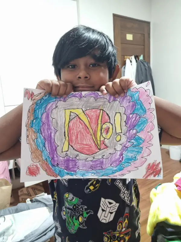 A learner holding up a bright drawing coloured in crayon
