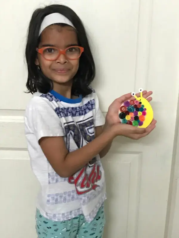 A learner holding a colourful clay craft