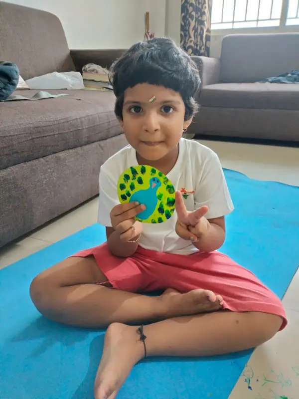 A young learner on a mat holding a round paper craft