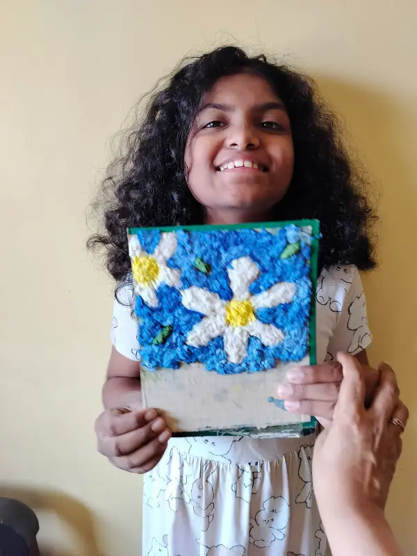 A learner holding her textured flower artwork