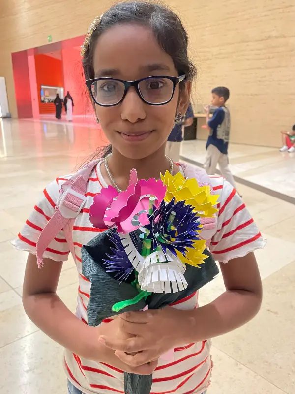 A learner holding a bouquet of paper flowers she made