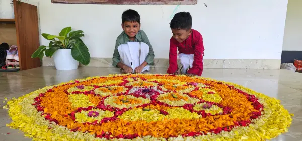 Learners making a large flower rangoli on the floor