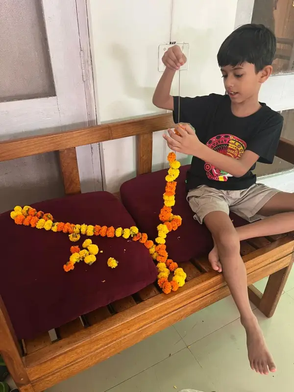 A learner stringing a marigold garland for a festival
