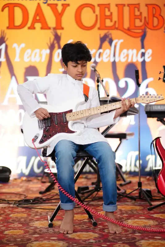 A learner playing electric guitar on stage at a school celebration