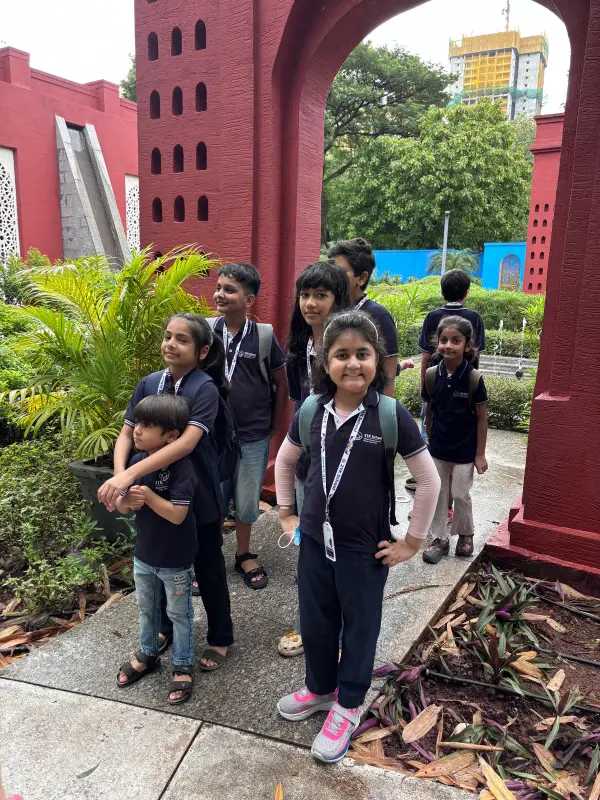 Learners in 21K School polos under a red arch on a field trip