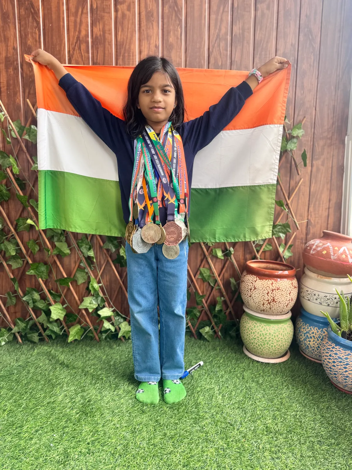 A learner wearing her medals in front of the Indian flag