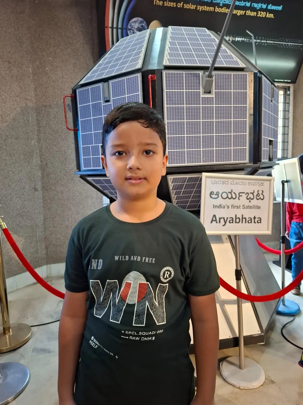 A learner beside a satellite model at a science museum