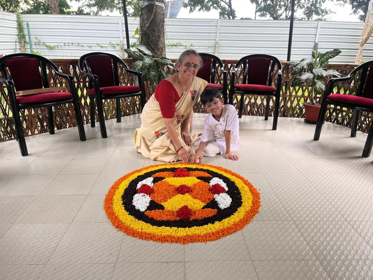 A young learner and an elder making a flower pookalam together