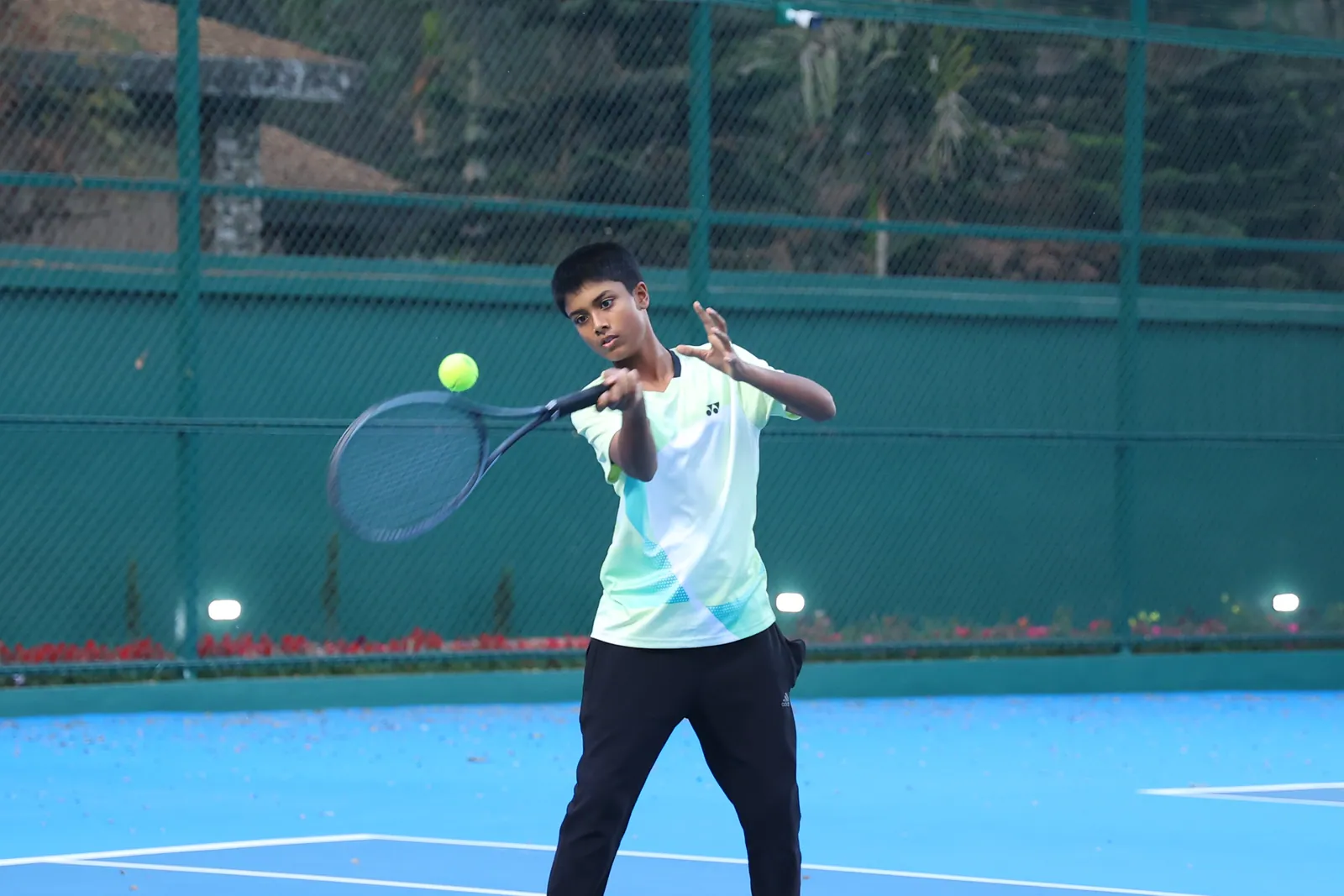 A learner playing a forehand on a tennis court