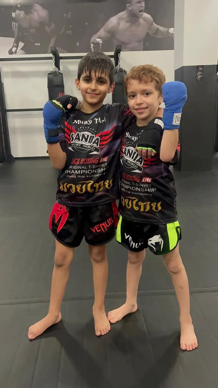 Two young friends in Muay Thai kit standing together at their gym