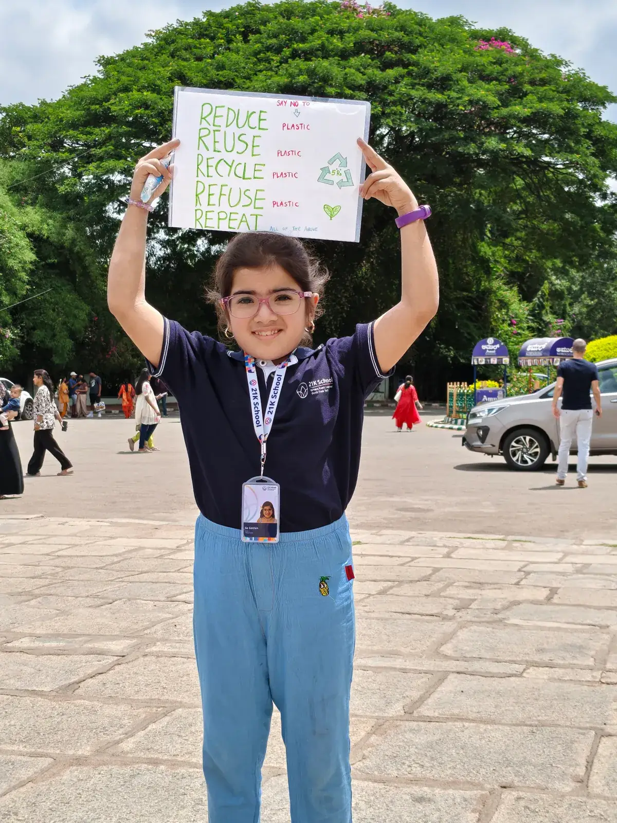 A learner holding up her Reduce, Reuse, Recycle placard outdoors