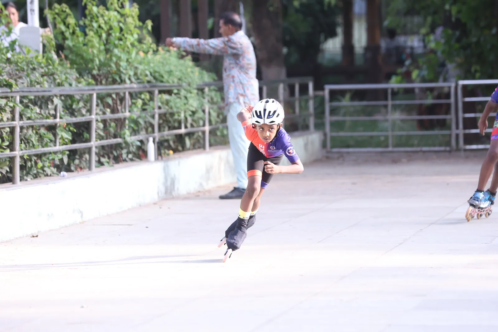 A learner inline speed skating with a coach watching behind