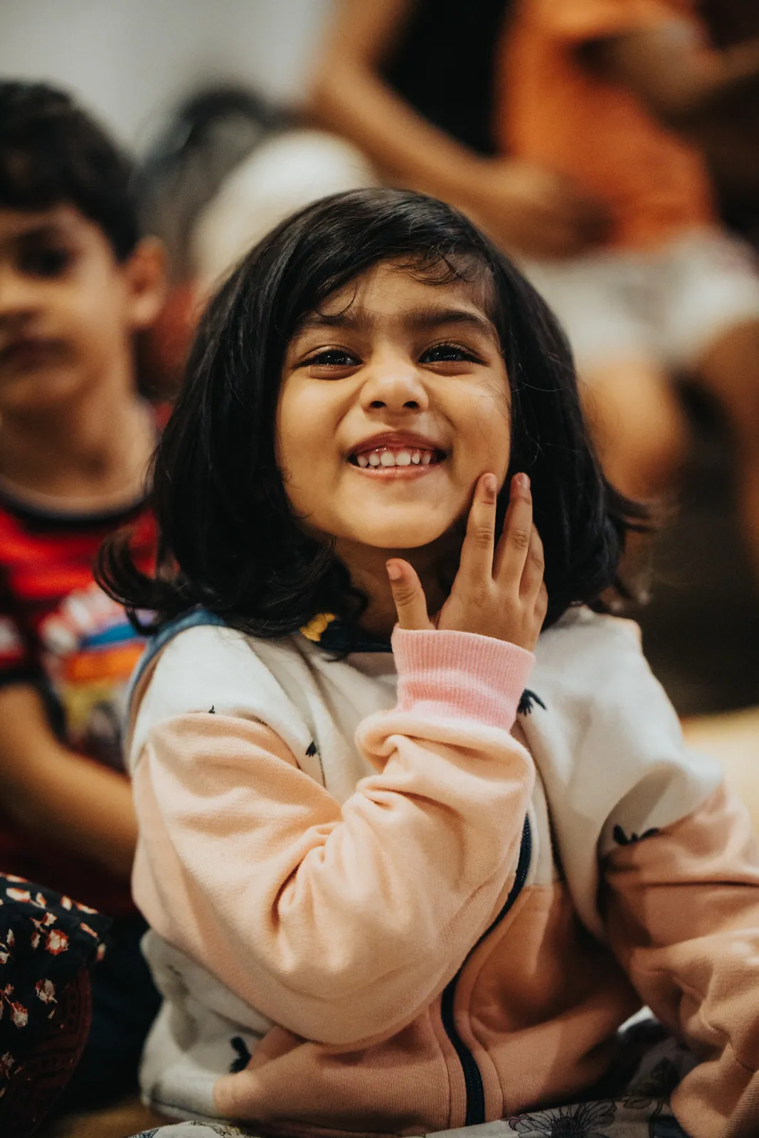 A young learner smiling and listening closely, chin in her hand